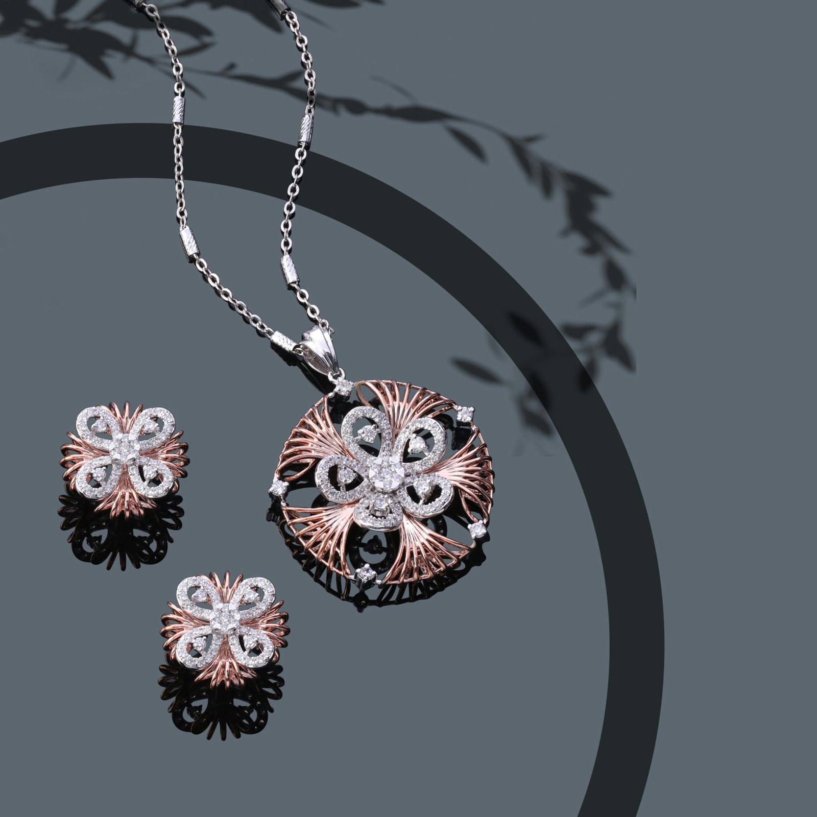 Intricate rose gold and diamond pendant with matching earrings on a sleek surface.